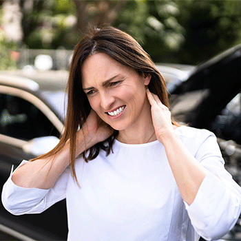 Woman with neck pain standing next to a car accident in Coral Springs, FL